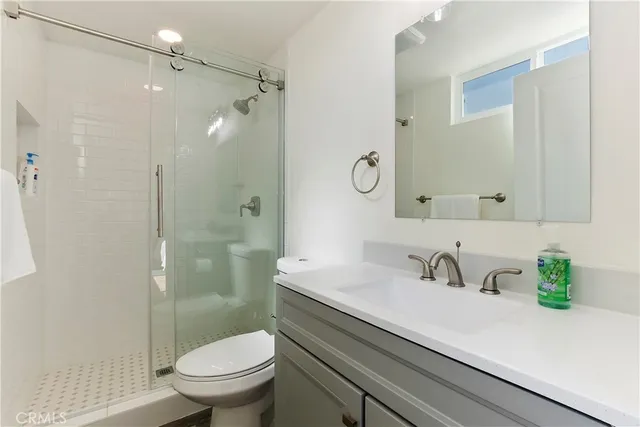 a bathroom with a sink a toilet a mirror and shower