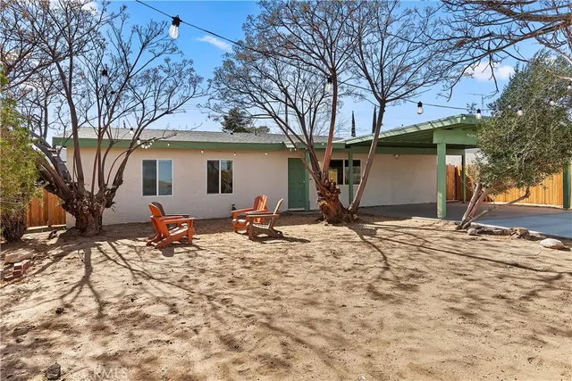 a backyard of a house with table and chairs under a large tree