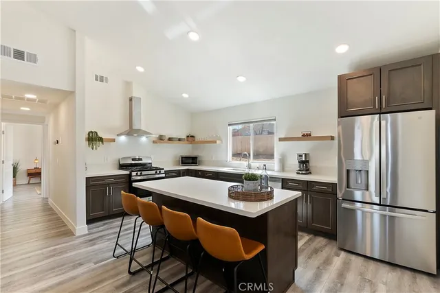 a kitchen with stainless steel appliances granite countertop a dining table chairs stove refrigerator and cabinets