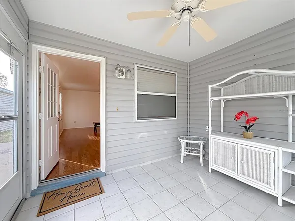 an empty room with wooden floor chandelier fan and windows