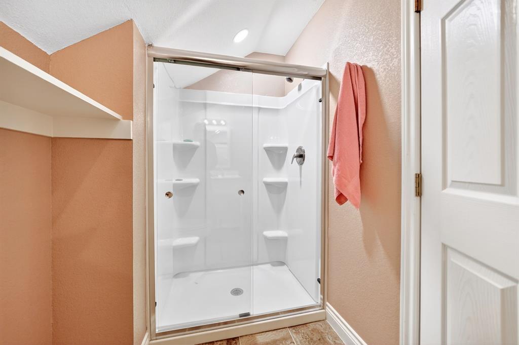 5230 Esquire Estates Road Mabank, TX 75156 - Photo 25 of 39 Shower enclosure with glass sliding doors, integrated shelving, and a chrome shower fixture