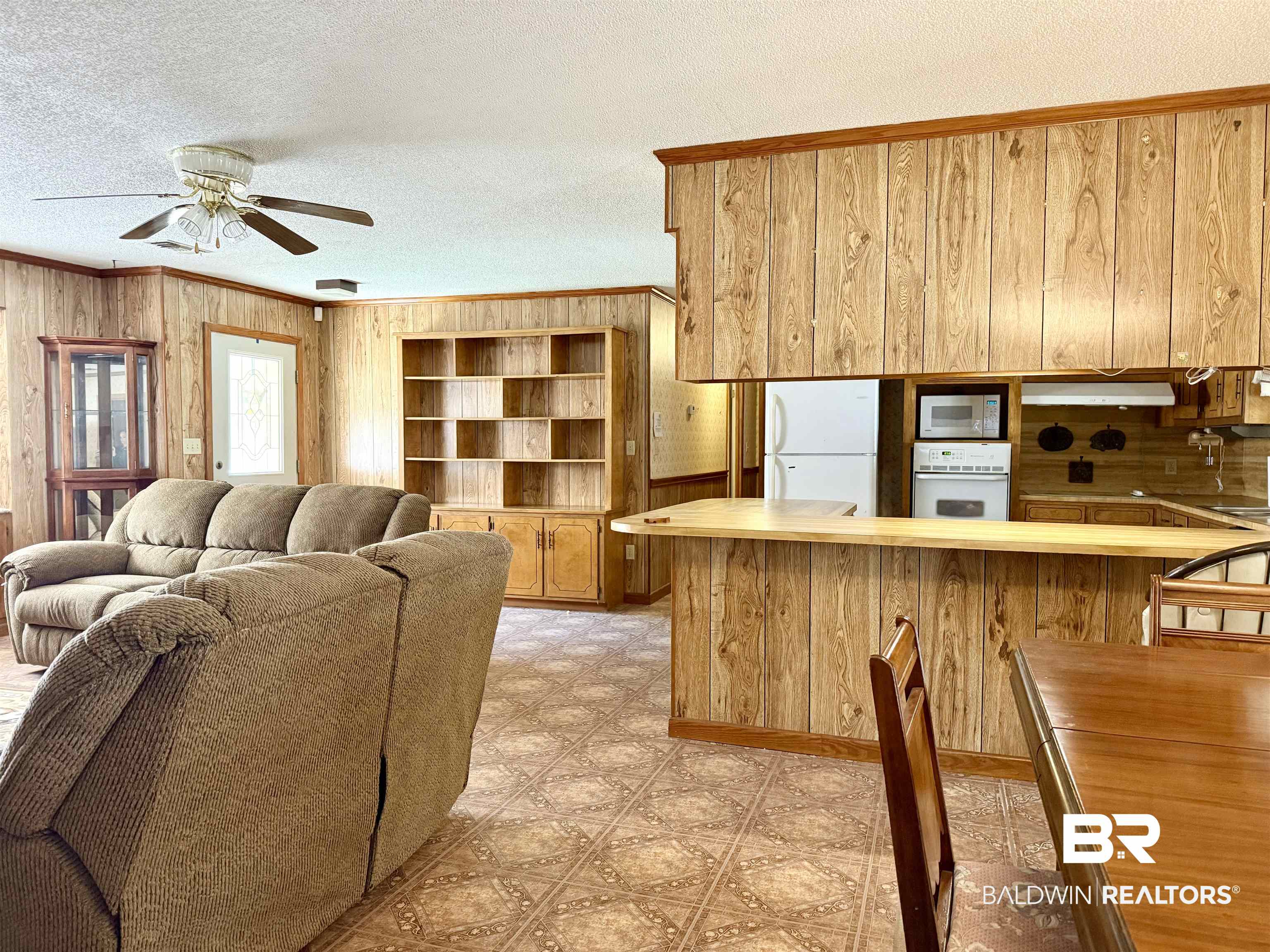 98 Evans Avenue Brewton, AL 36426 - Photo 3 of 18 Living room featuring ornamental molding, a textured ceiling, light floors, wood walls, and a ceiling fan