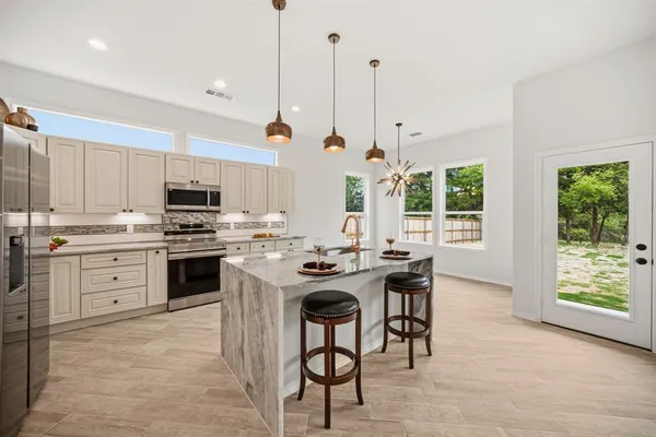 a kitchen with stainless steel appliances kitchen island granite countertop a stove a sink and a refrigerator with wooden floor