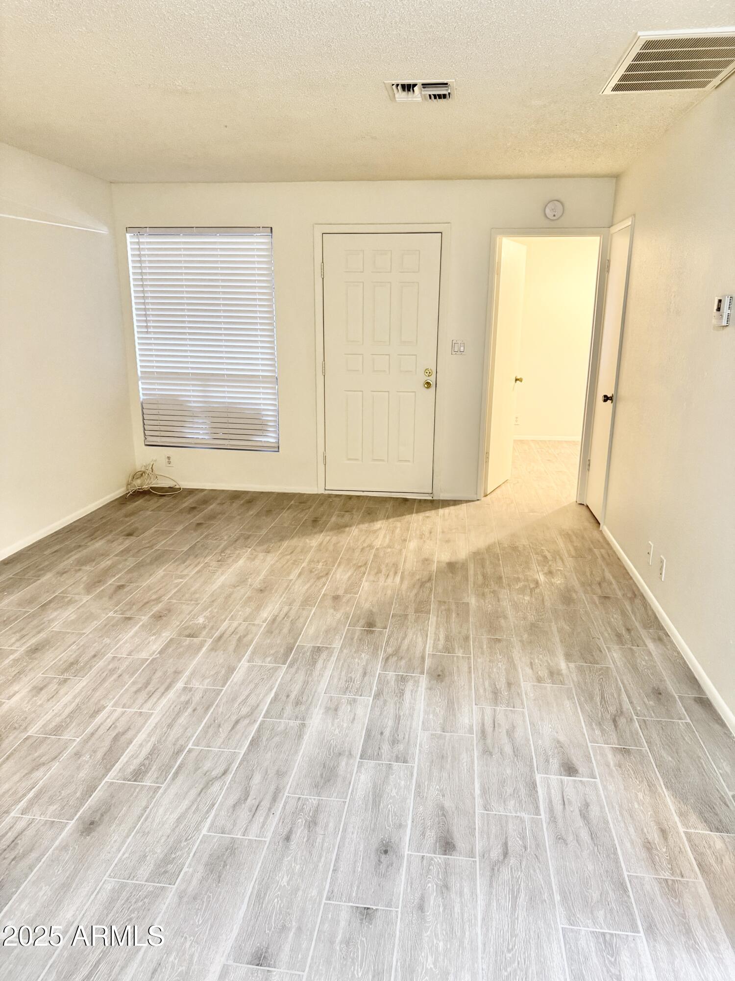 9015 West Elm Street, Unit 2 Phoenix, AZ 85037 - Photo 4 of 32 an empty room with wooden floor and windows
