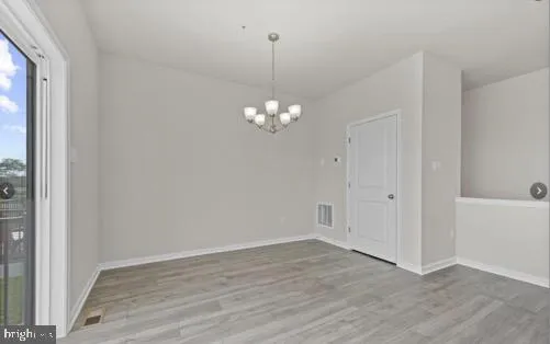a view of a chandelier in big room with wooden floor and chandelier