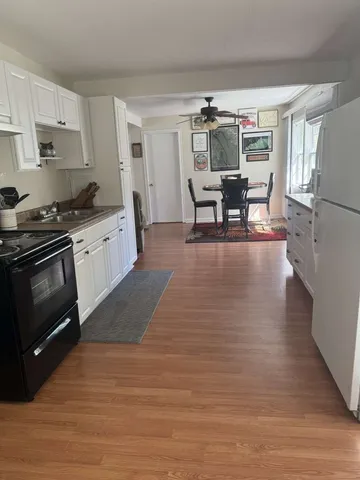 a kitchen with stainless steel appliances granite countertop a stove a refrigerator a sink dishwasher a dining table and chairs with wooden floor