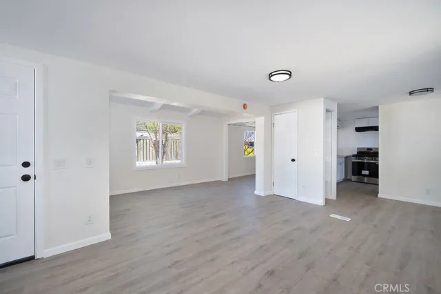 a view of an empty room with a window and wooden floor
