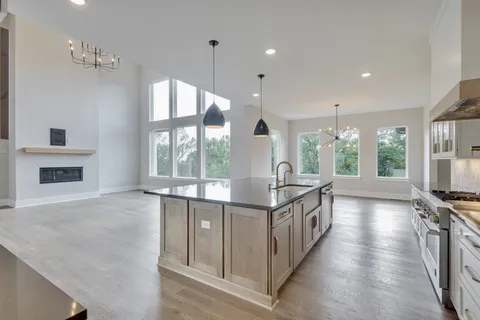 a large kitchen with kitchen island a large window a sink and stainless steel appliances