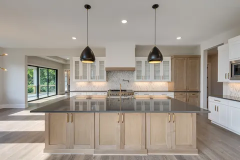 a kitchen with stainless steel appliances granite countertop a stove a sink and a wooden floors