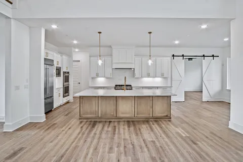 a large kitchen with cabinets wooden floor and a sink