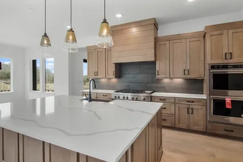 a kitchen with stainless steel appliances granite countertop a sink a stove and a wooden floors