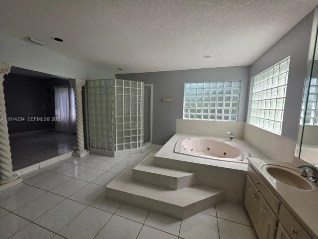 a spacious bathroom with a tub sink and mirror