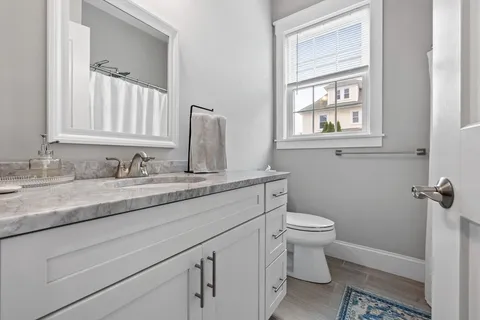 a bathroom with a granite countertop toilet sink and mirror