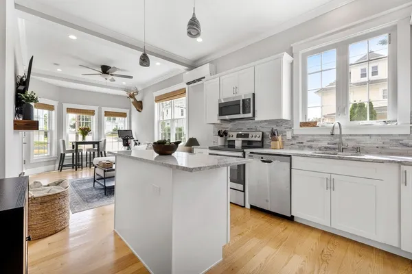 a kitchen with stainless steel appliances granite countertop a stove top oven a sink dishwasher and white cabinets with wooden floor