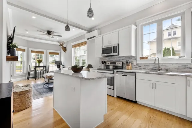 a kitchen with stainless steel appliances granite countertop a stove top oven a sink dishwasher and white cabinets with wooden floor