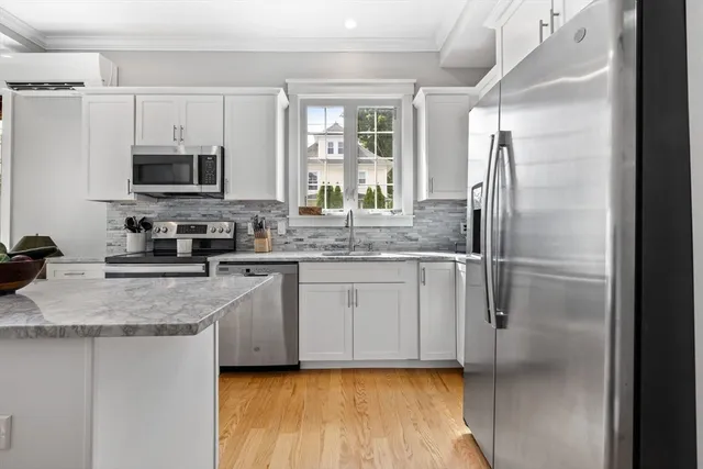 a kitchen with stainless steel appliances granite countertop a refrigerator a sink and white cabinets