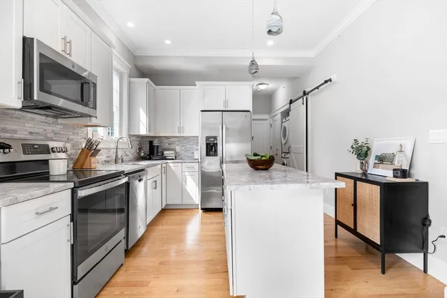 a kitchen with stainless steel appliances kitchen island granite countertop a sink a stove top oven a counter space and cabinets