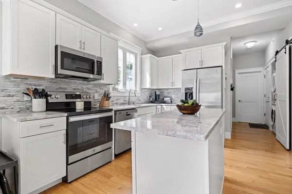 a kitchen with stainless steel appliances granite countertop a sink a stove a refrigerator a center island with wooden floor and cabinets