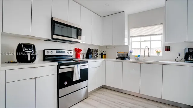 a kitchen with stainless steel appliances granite countertop white cabinets a sink and a window