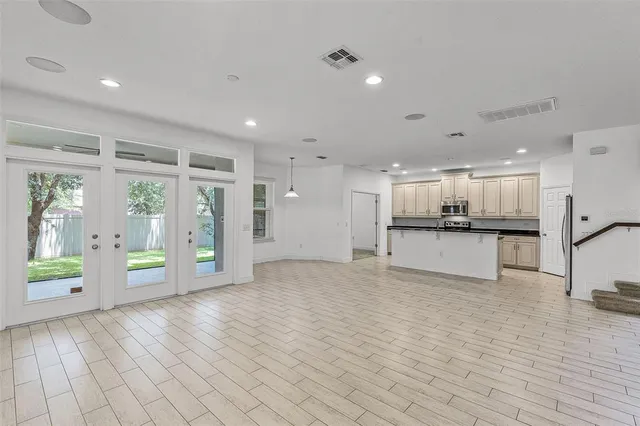 a view of an empty room with kitchen and window