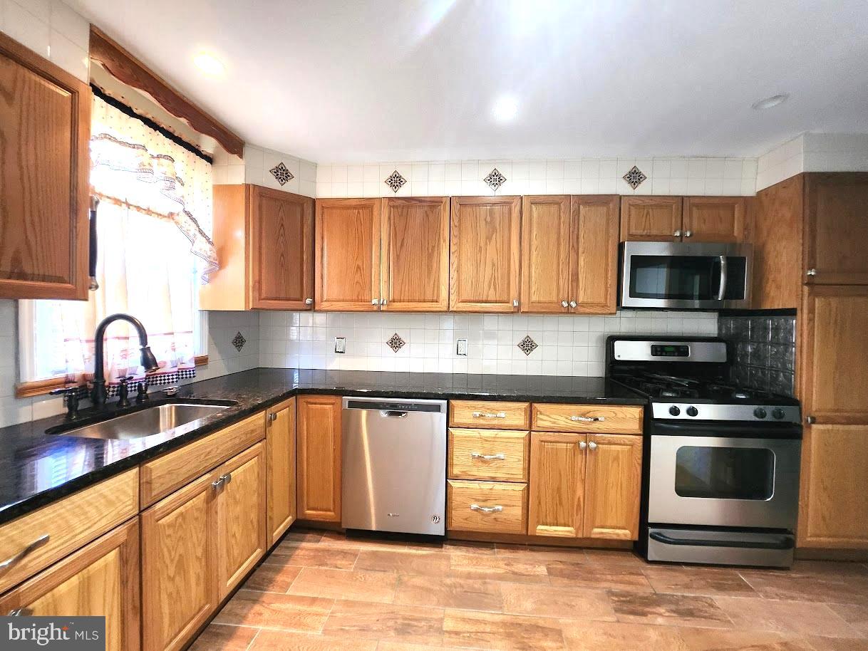 a kitchen with stainless steel appliances granite countertop a stove a sink dishwasher and a microwave oven with cabinets