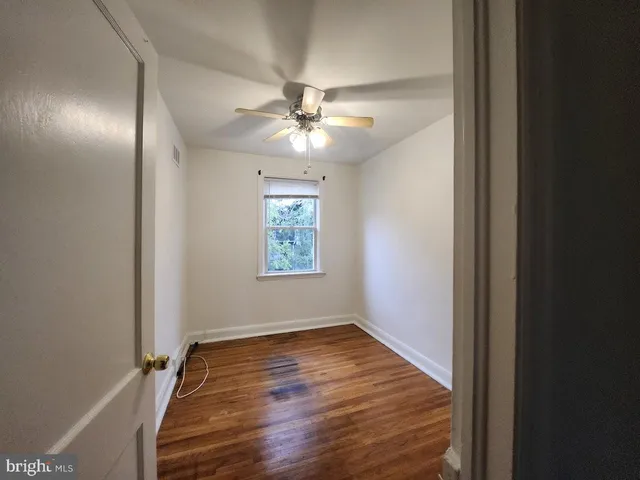 an empty room with wooden floor chandelier fan and windows
