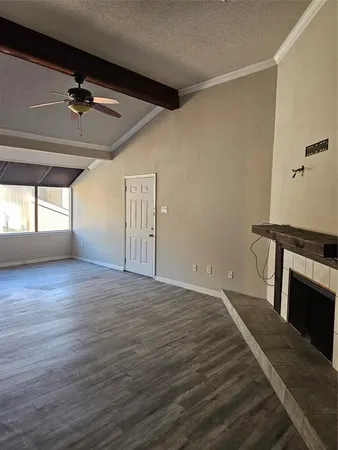 a view of an empty room with wooden floor and a fireplace