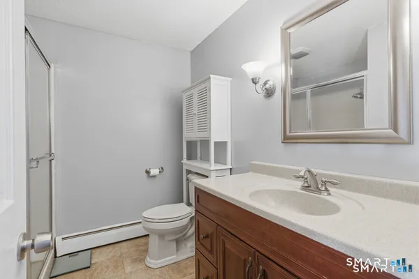 a bathroom with a granite countertop sink a toilet and a mirror