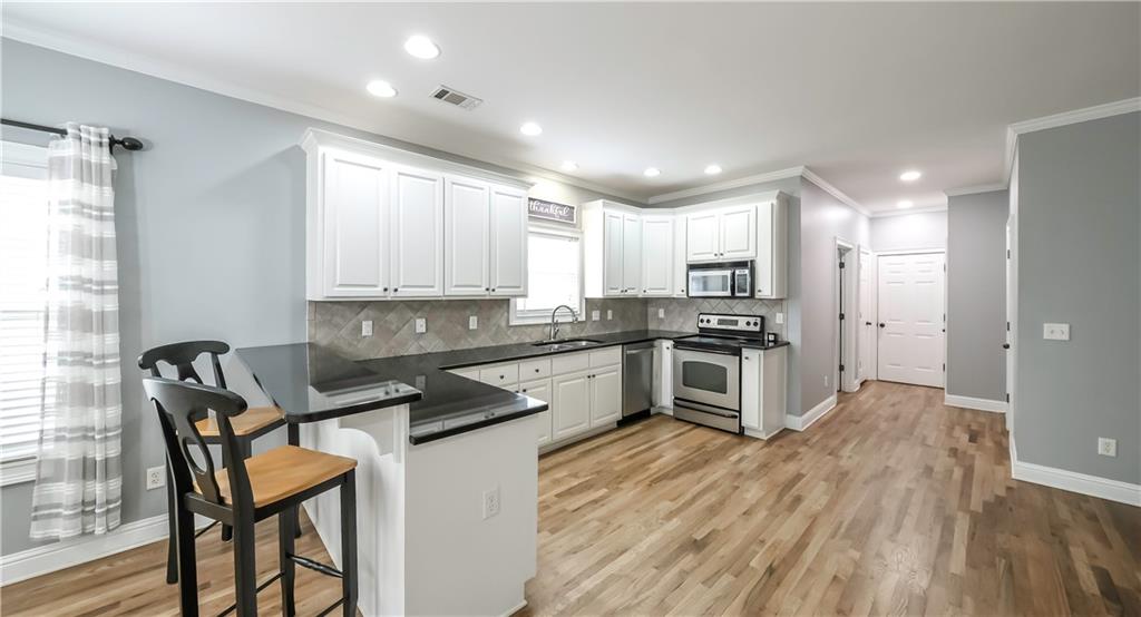 896 Winn Road Douglasville, GA 30134 - Photo 11 of 64 a kitchen with granite countertop a stove top oven a sink dishwasher a dining table and chairs with wooden floor