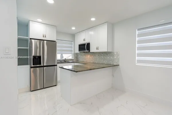 a kitchen with stainless steel appliances granite countertop a refrigerator and a sink