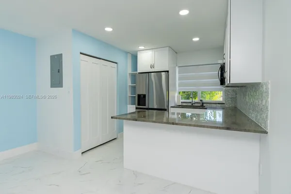 a kitchen with stainless steel appliances granite countertop a sink and a refrigerator