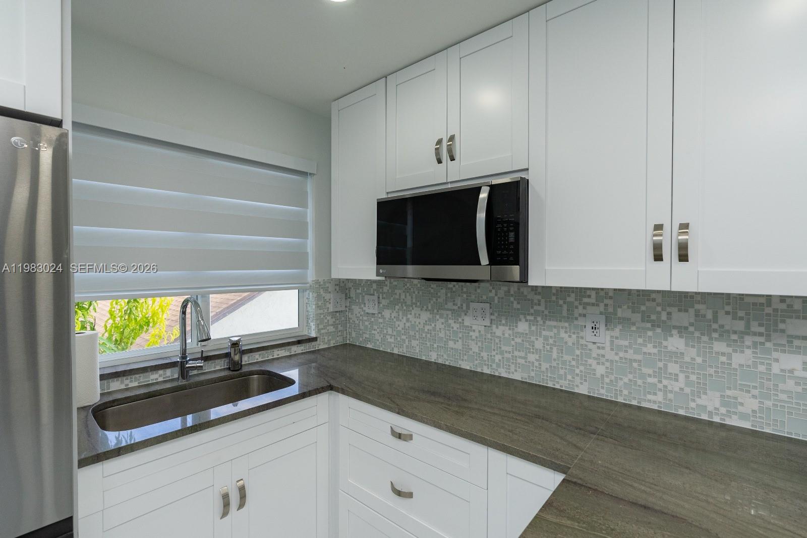 13270 Southwest 103rd Terrace, Unit 2 Miami, FL 33186 - Photo 16 of 41 a kitchen with granite countertop white cabinets and white appliances