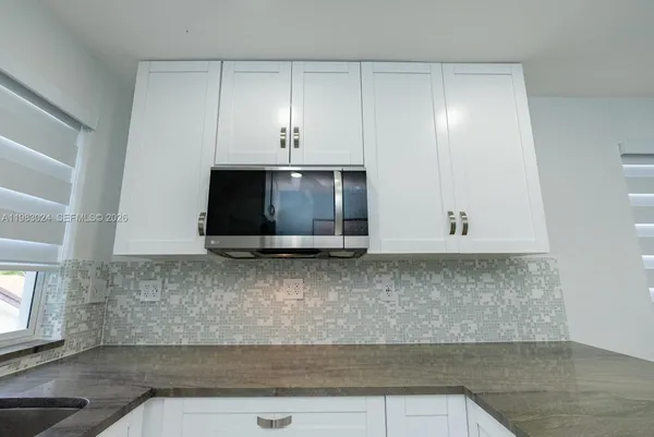 a kitchen with a sink a microwave and cabinets