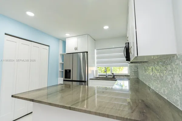 a kitchen with stainless steel appliances granite countertop a refrigerator and a sink