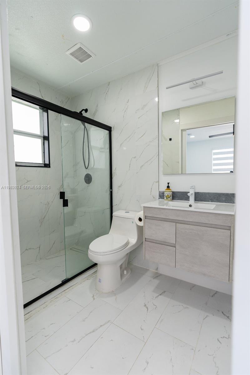 13270 Southwest 103rd Terrace, Unit 2 Miami, FL 33186 - Photo 36 of 41 a bathroom with a toilet a sink and glass door