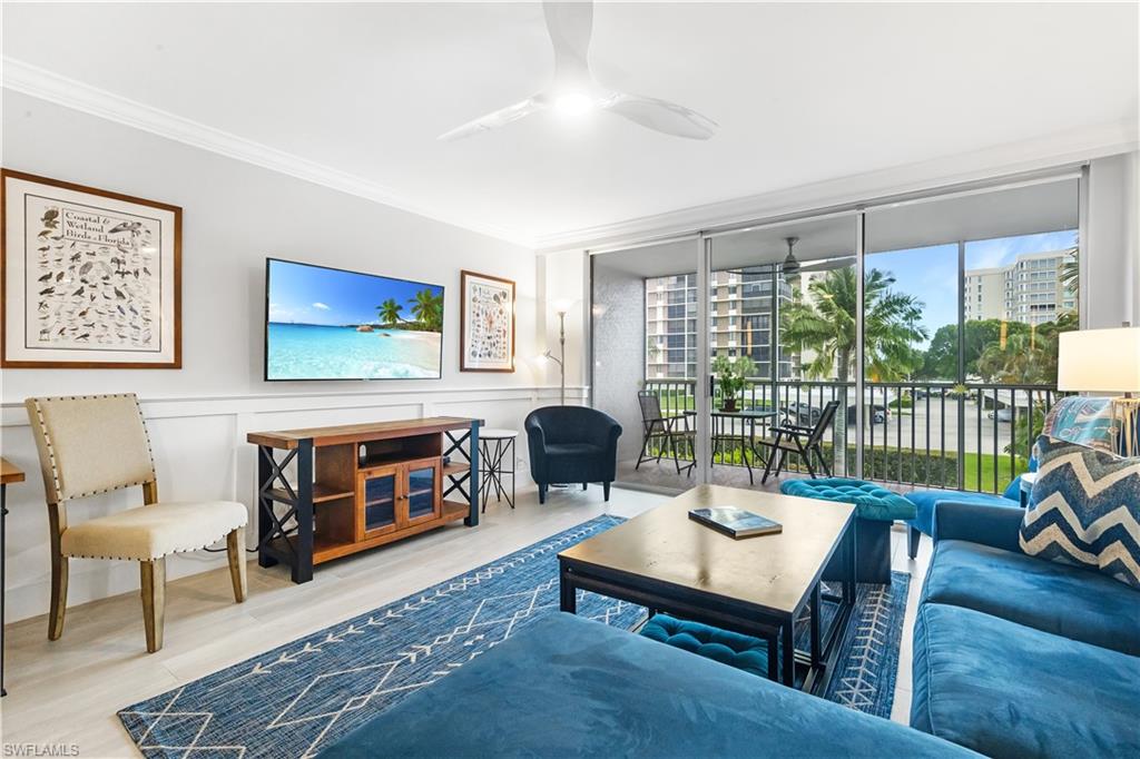 5 Bluebill Avenue, Unit 209 Naples, FL 34108 - Photo 12 of 32 a living room with furniture a flat screen tv and a floor to ceiling window