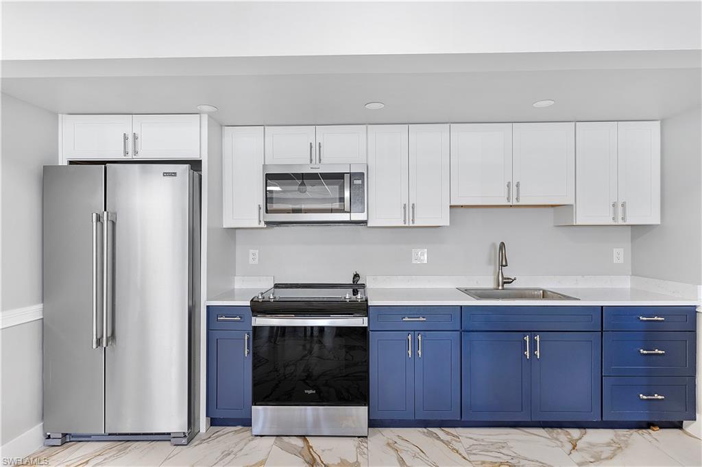 5 Bluebill Avenue, Unit 209 Naples, FL 34108 - Photo 22 of 32 a kitchen with a sink a refrigerator and cabinets
