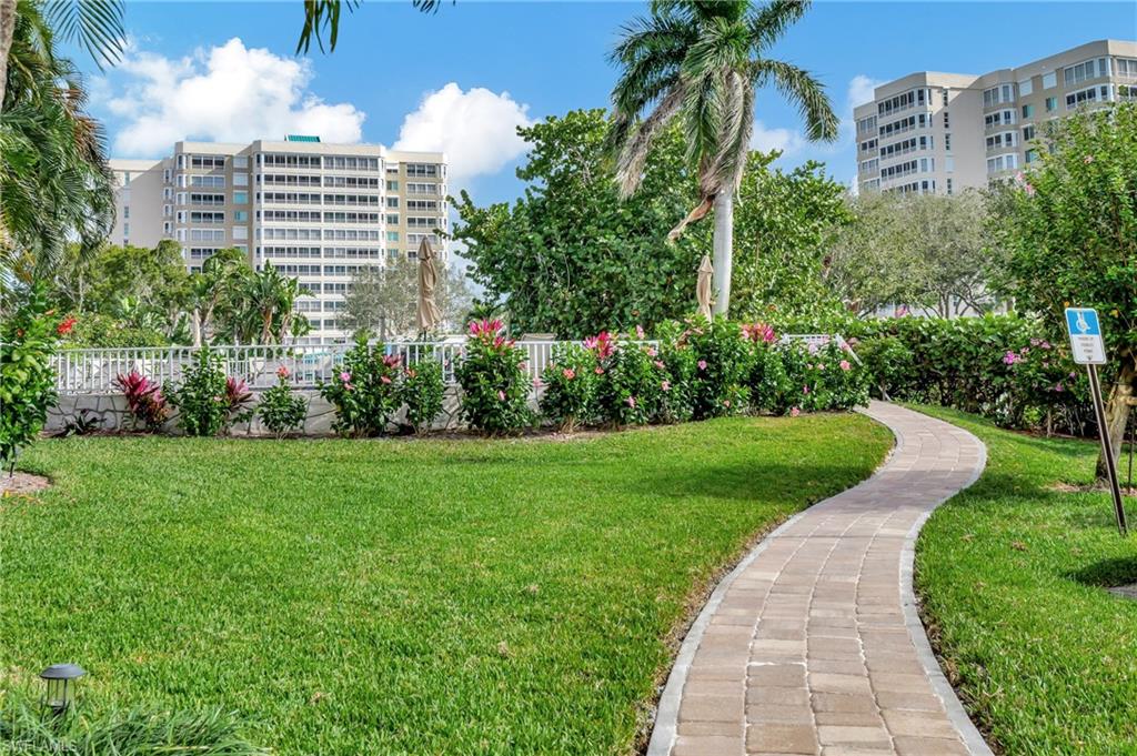 5 Bluebill Avenue, Unit 209 Naples, FL 34108 - Photo 28 of 32 a view of a garden with a building in the background