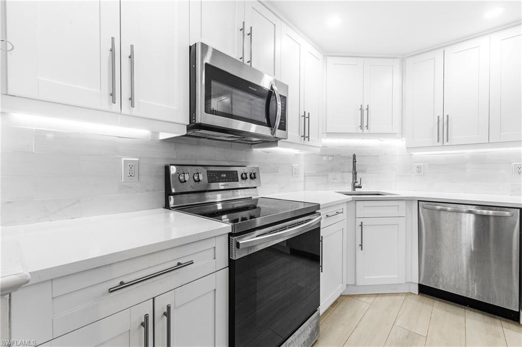 5 Bluebill Avenue, Unit 209 Naples, FL 34108 - Photo 6 of 32 a kitchen with cabinets stainless steel appliances and a sink
