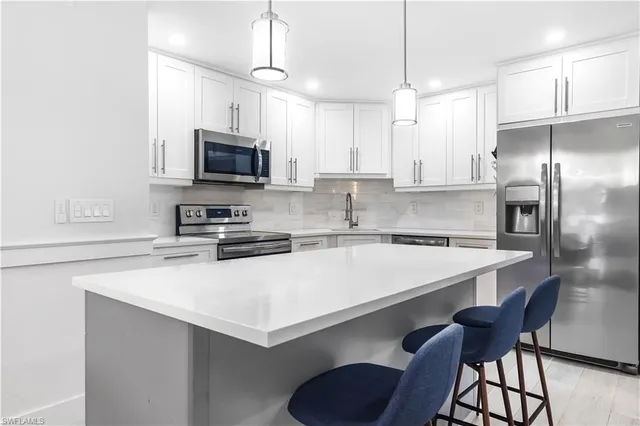 a kitchen with stainless steel appliances a stove a sink a microwave a refrigerator and cabinets