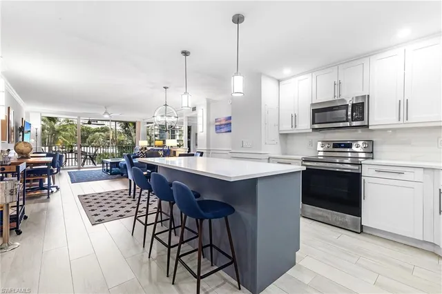 a kitchen with stainless steel appliances granite countertop a stove a sink dishwasher a refrigerator with a dining table and chairs