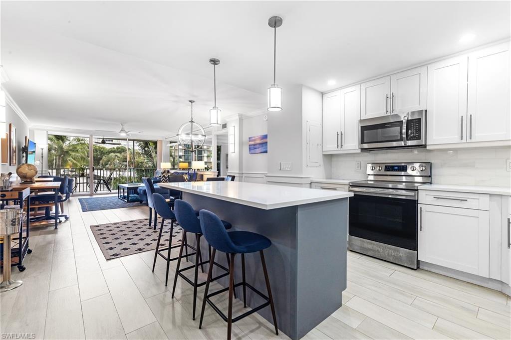 5 Bluebill Avenue, Unit 209 Naples, FL 34108 - Photo 8 of 32 a kitchen with stainless steel appliances granite countertop a stove a sink dishwasher a refrigerator with a dining table and chairs