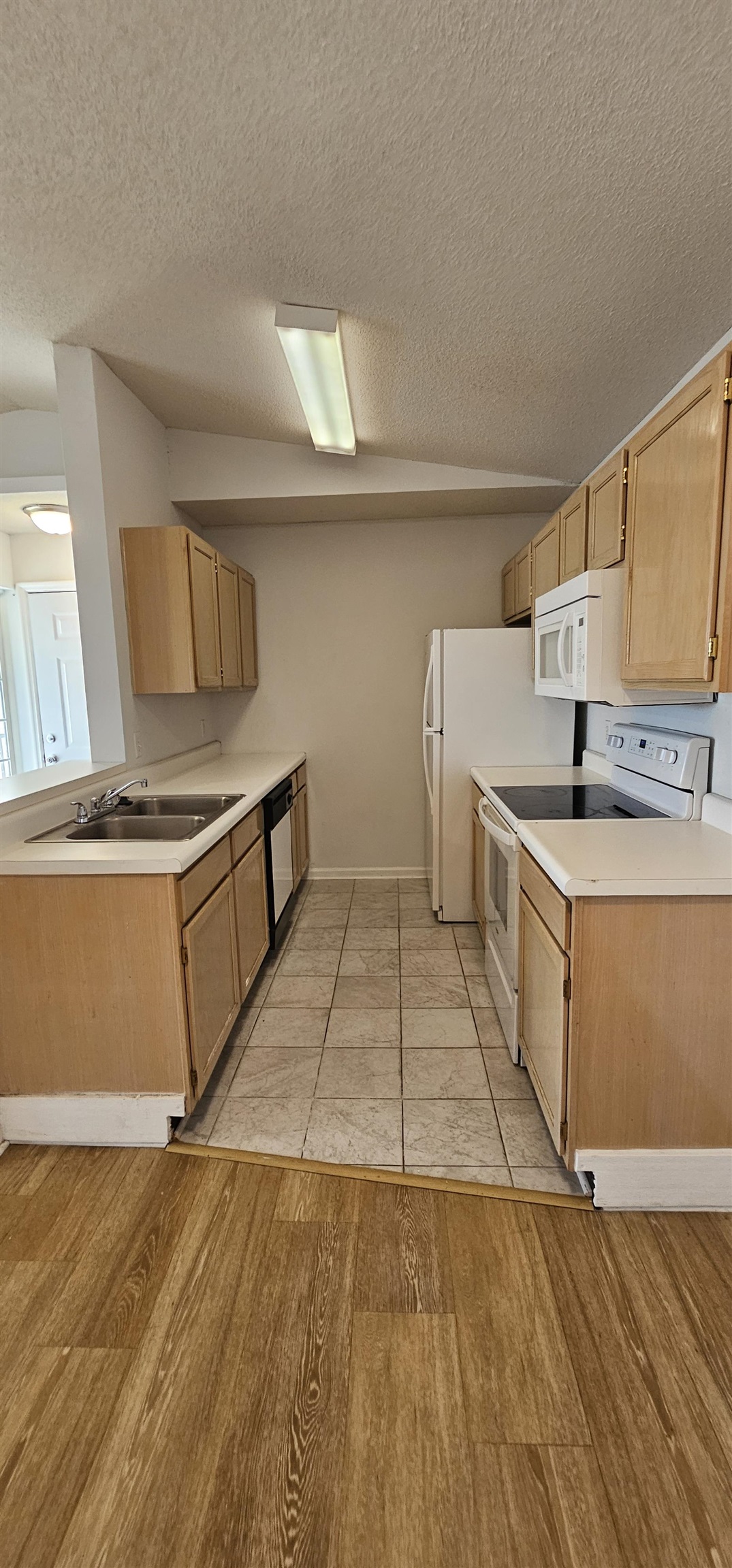 2273 Huntingdon Drive, Unit J Myrtle Beach, SC 29575 - Photo 5 of 24 Kitchen featuring light brown cabinets, white appliances, light countertops, light wood-style flooring, and a textured ceiling