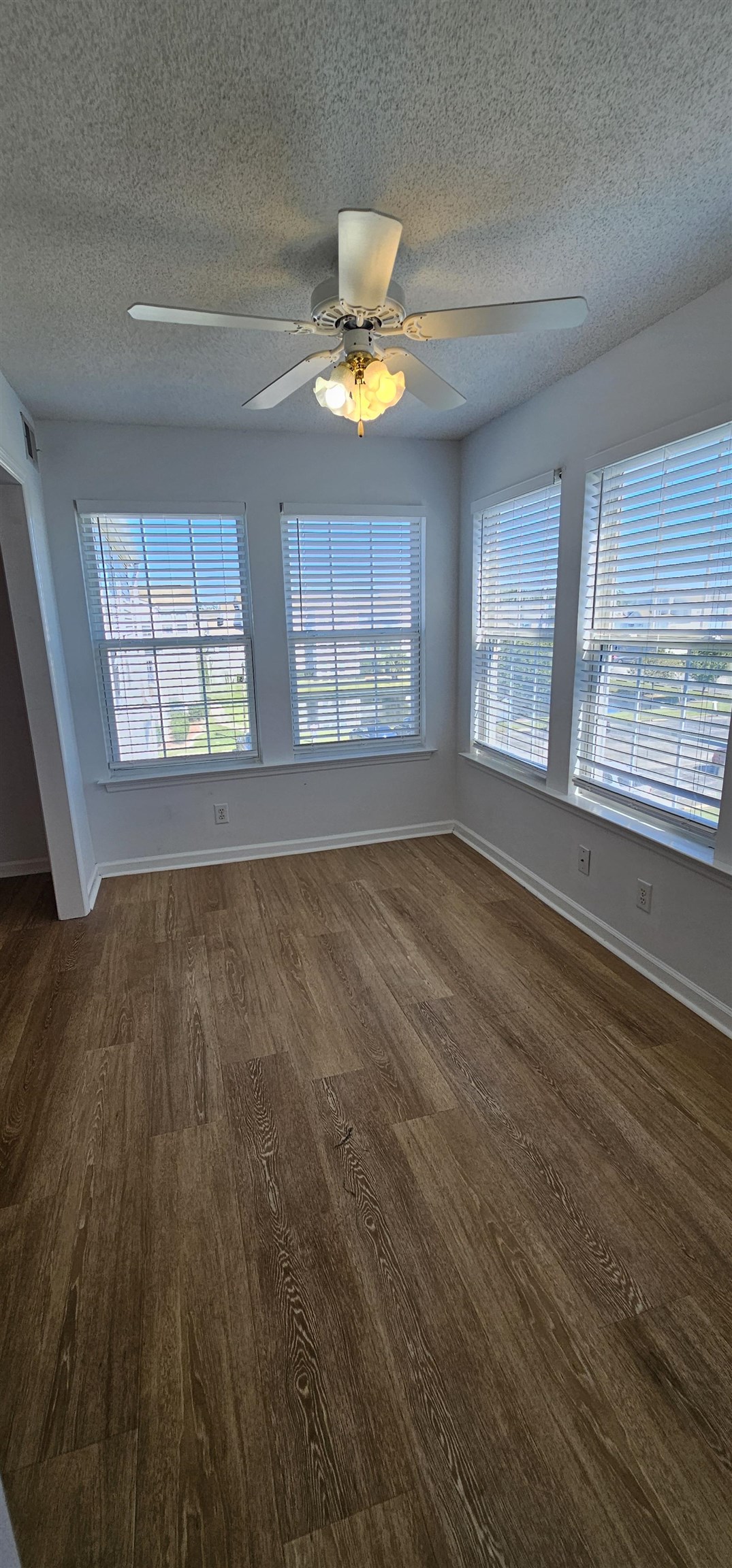 2273 Huntingdon Drive, Unit J Myrtle Beach, SC 29575 - Photo 8 of 24 Empty room featuring healthy amount of natural light, a textured ceiling, a ceiling fan, and dark wood finished floors