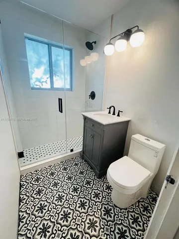 a bathroom with a sink a toilet a mirror and shower