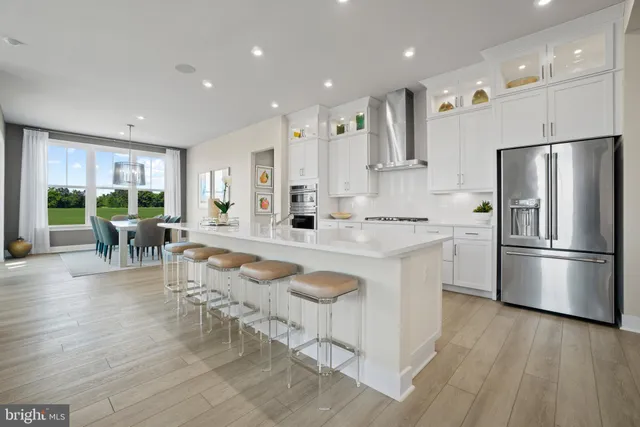 a kitchen with stainless steel appliances granite countertop a refrigerator a stove a sink a dining table and chairs with wooden floor