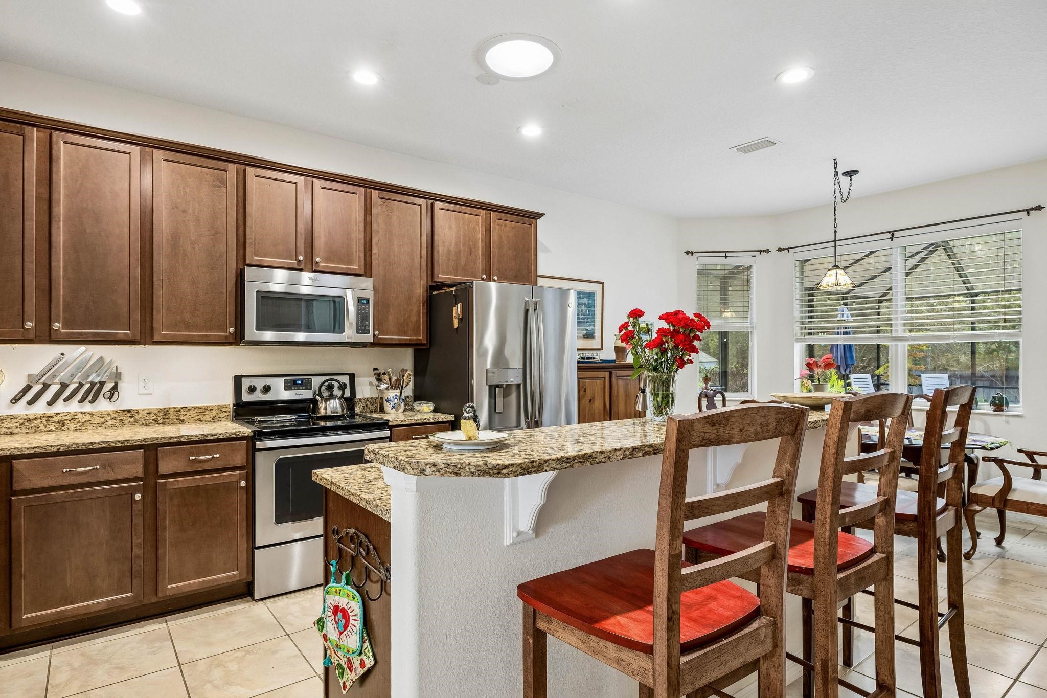 133 South Twin Maple Road St. Augustine, FL 32084 - Photo 8 of 34 Kitchen with stainless steel appliances, a breakfast bar, light tile patterned flooring, pendant lighting, and light stone countertops