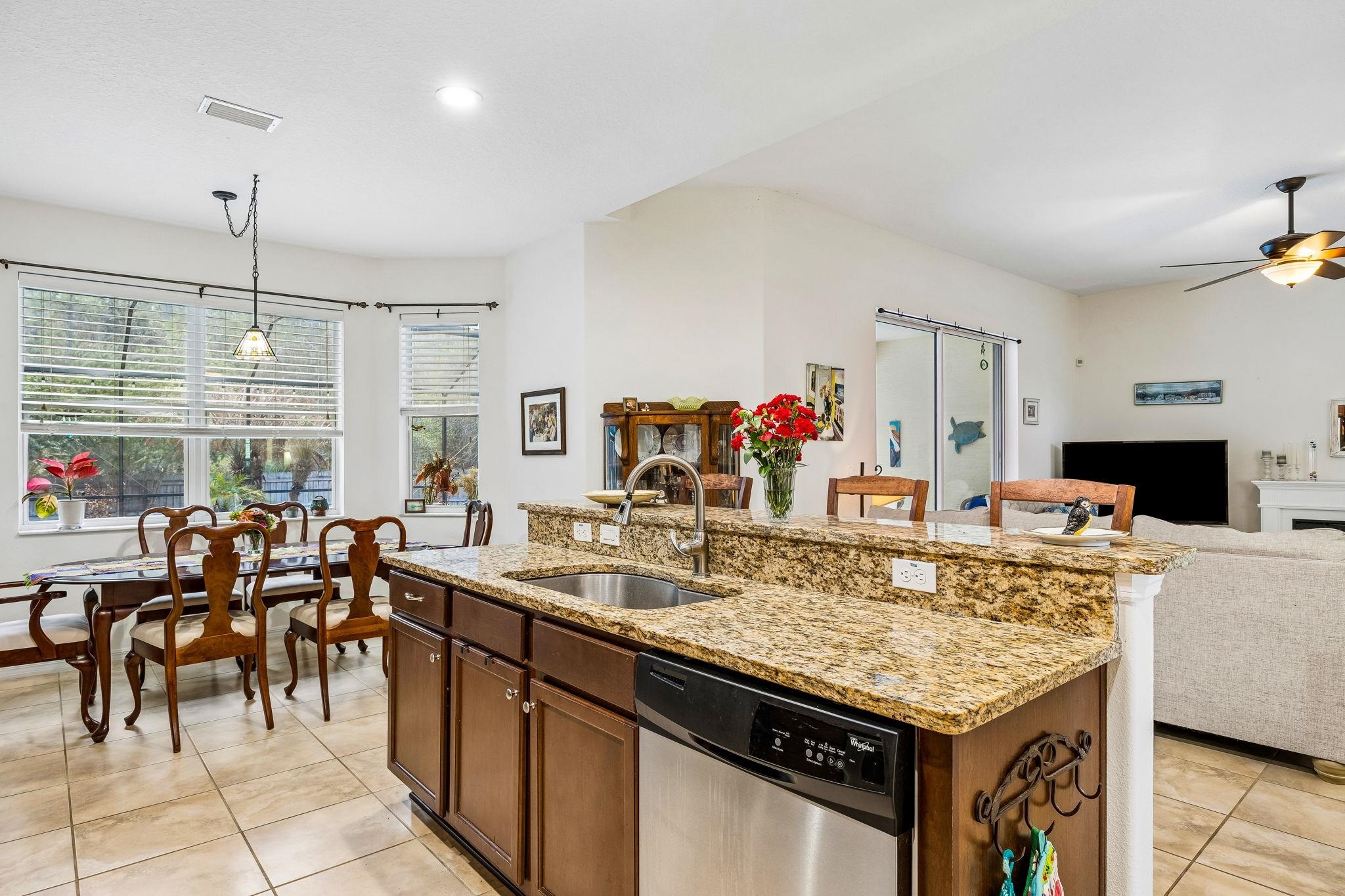 133 South Twin Maple Road St. Augustine, FL 32084 - Photo 33 of 34 Kitchen with open floor plan, light stone countertops, stainless steel dishwasher, an island with sink, and decorative light fixtures