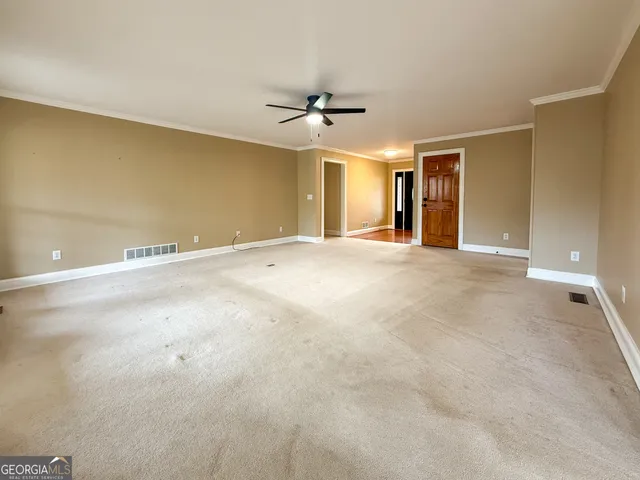 an empty room with ceiling fan and window