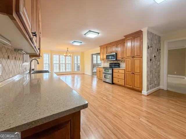 a kitchen with stainless steel appliances granite countertop a refrigerator a stove and a wooden floors